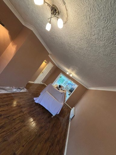 Living room Walls - After Narrow hallway with wooden flooring, light fixtures, and a white covered furniture piece.